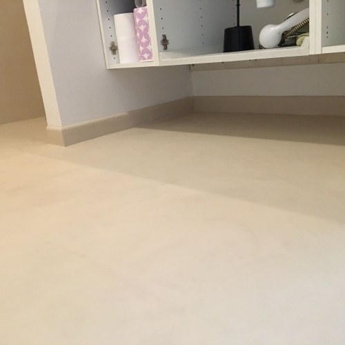 Vaskemiljø efter renovering – microcement på gulv og sokkel skaber stilrent badeværelse.