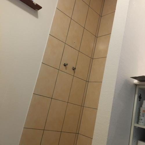Førbillede af badeværelse med klinker i bruseniche – klar til renovering med silkecement af murer i Ølgod.