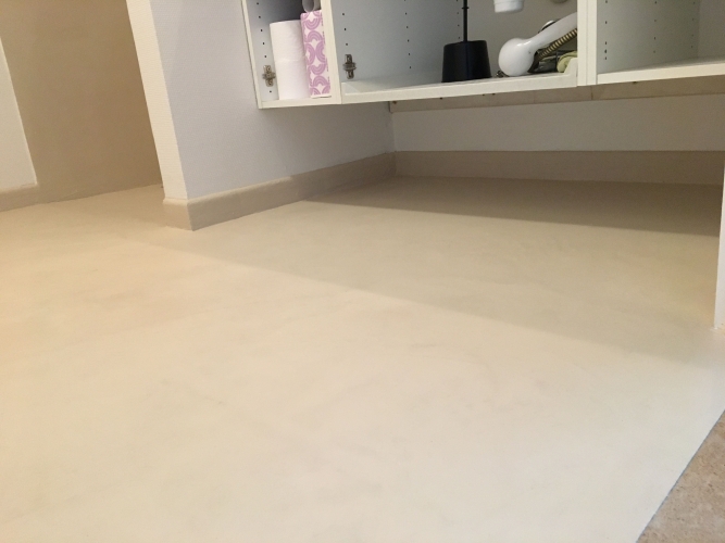 Vaskemiljø efter renovering – microcement på gulv og sokkel skaber stilrent badeværelse.