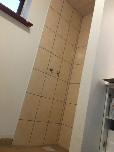 Førbillede af badeværelse med klinker i bruseniche – klar til renovering med silkecement af murer i Ølgod.